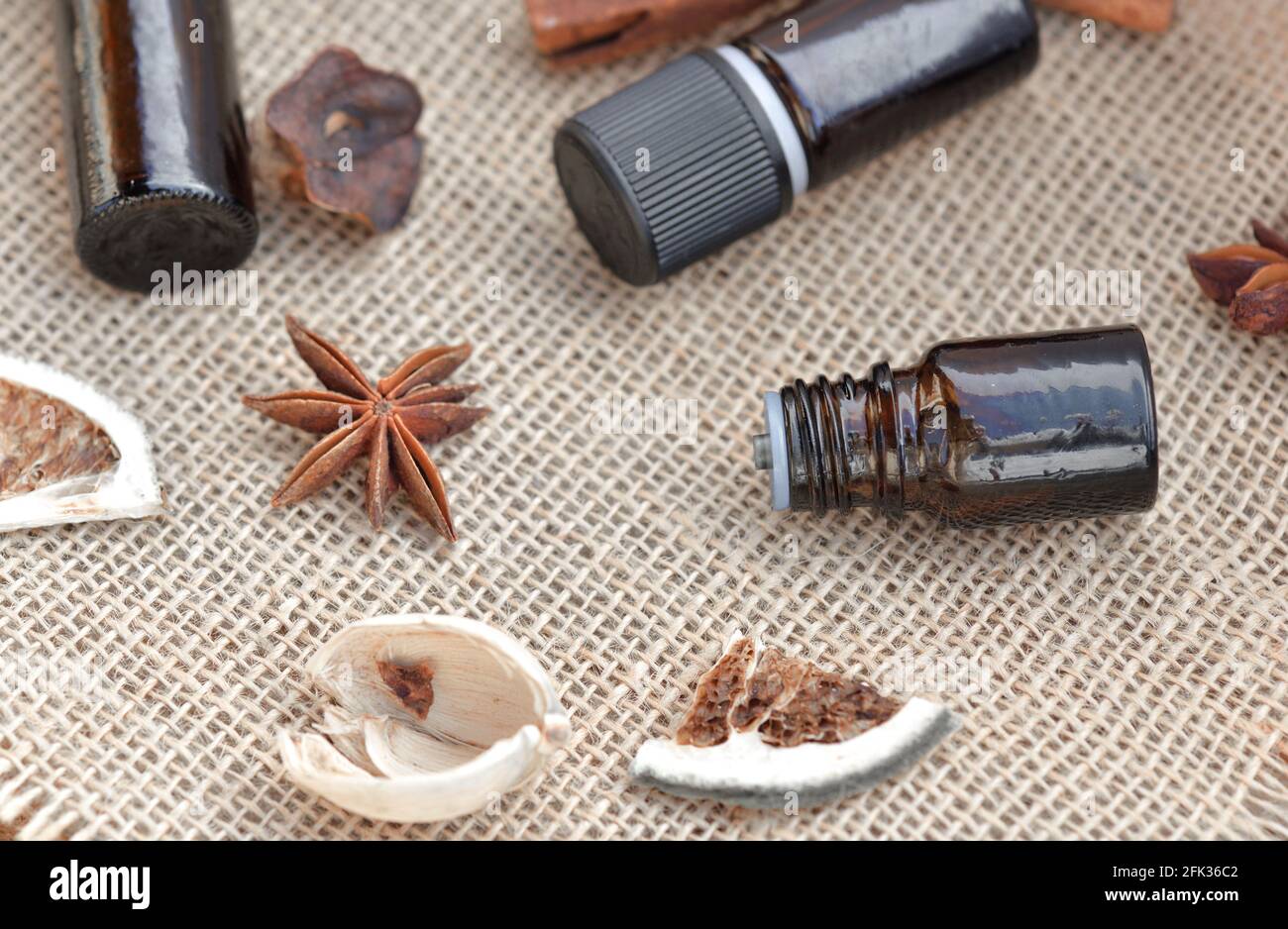 bouteilles d'huile essentielle avec; bâton de cannelle; badian; et fruits secs avec coquille; sur un fond de tissu naturel Banque D'Images