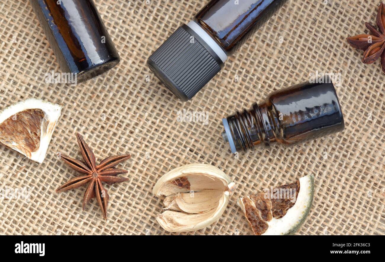 vue de dessus sur les bouteilles d'huile essentielle avec bâton de cannelle, badian et fruits secs avec coquille sur un fond de tissu naturel Banque D'Images