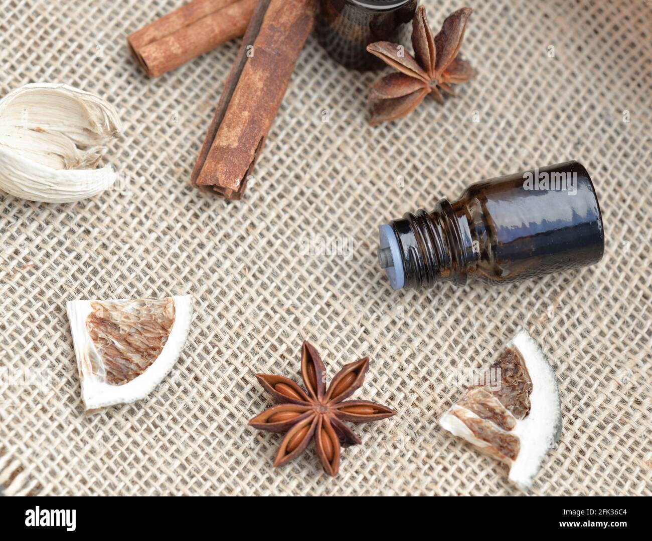 vue de dessus sur les bouteilles d'huile essentielle avec bâton de cannelle, badian et fruits secs avec coquille sur un fond de tissu naturel Banque D'Images
