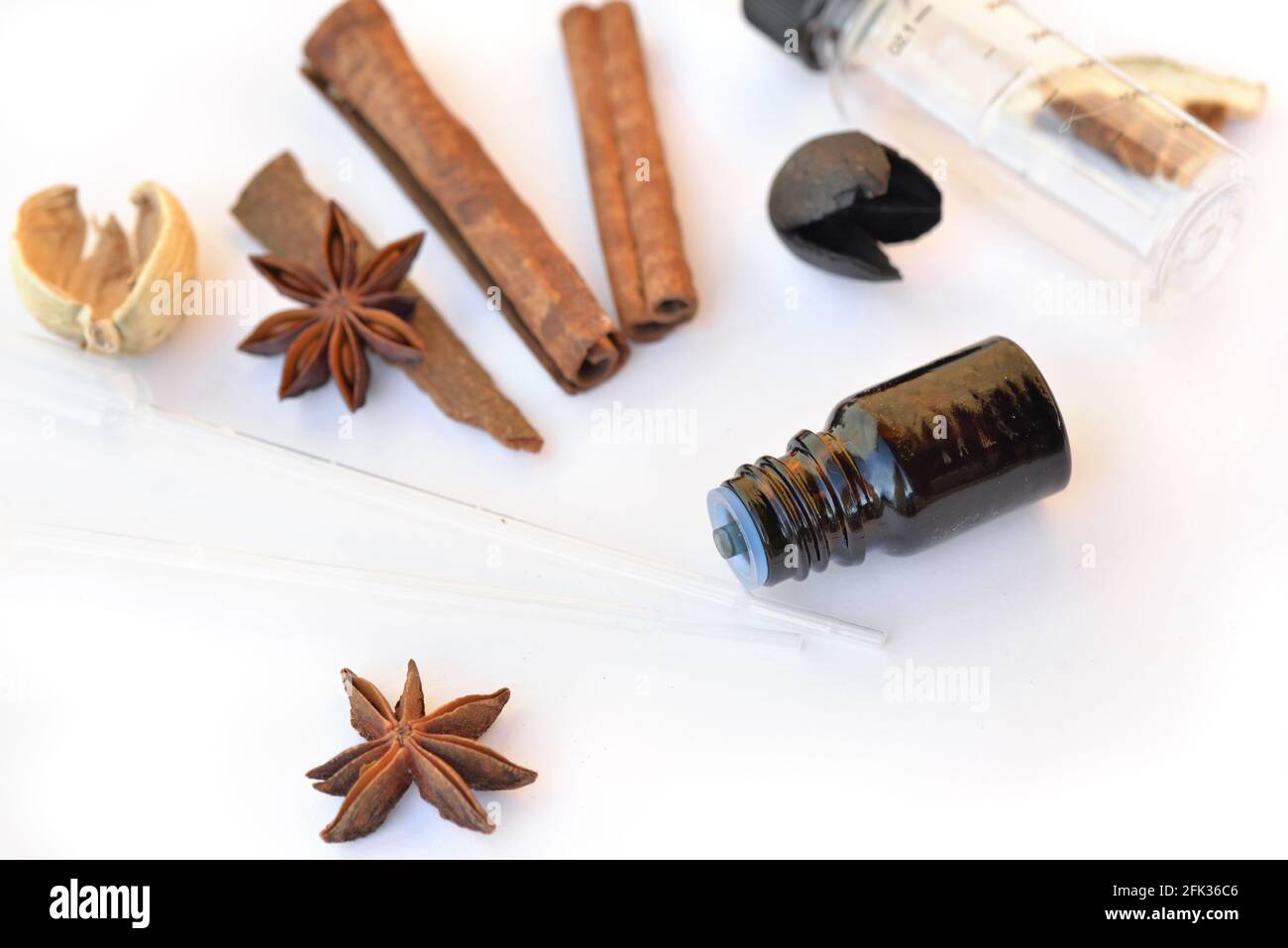 bouteille d'huile essentielle et de cannelle et d'anis sur un fond blanc avec pipette pour extraire l'essence Banque D'Images