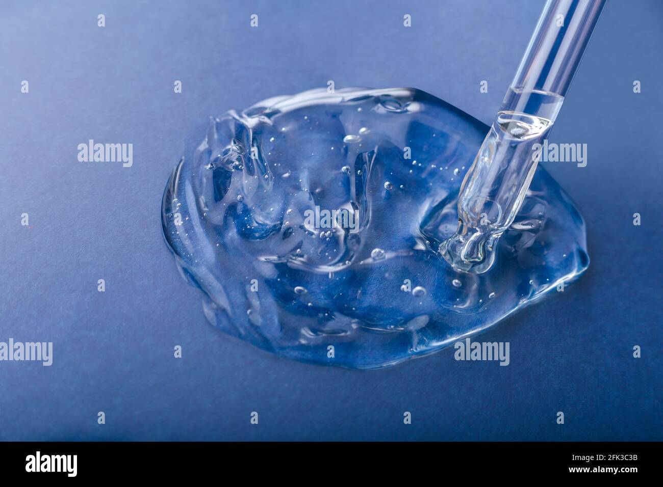 Gel échantillon de texture de sérum produit cosmétique pour la santé de la peau dans la pipette. Collagène en gel transparent avec compte-gouttes sur fond bleu. Échantillon de produit chimique Banque D'Images