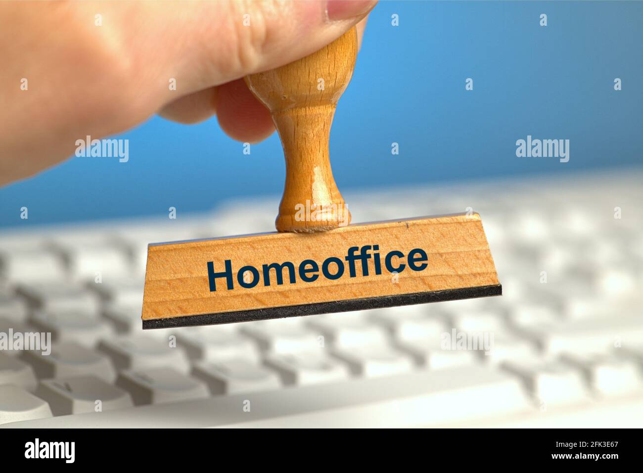 Allemagne. 22 avril 2021. Un timbre en bois avec l'inscription « Homeoffice », tenu par une main dans un fond perdu sur un clavier d'ordinateur blanc. Photo avec composition sur fond bleu. Le bureau à domicile est à l'ordre du jour et est recommandé par des experts dans la mesure du possible. | utilisation dans le monde crédit: dpa/Alay Live News Banque D'Images