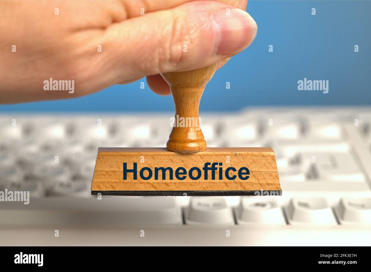 Allemagne. 22 avril 2021. Un timbre en bois avec l'inscription « Homeoffice », tenu par une main dans un fond perdu sur un clavier d'ordinateur blanc. Photo avec composition sur fond bleu. Le bureau à domicile est à l'ordre du jour et est recommandé par des experts dans la mesure du possible. | utilisation dans le monde crédit: dpa/Alay Live News Banque D'Images