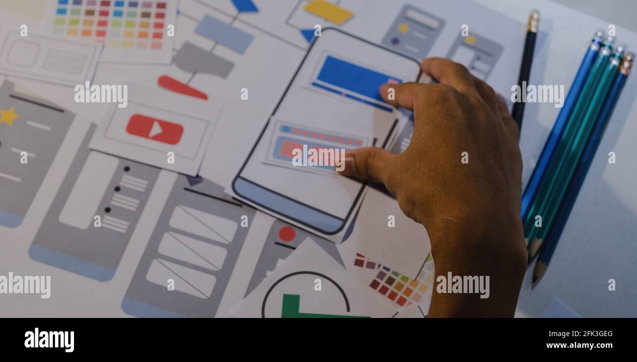 Concepteurs dessinant le concept de développement d'applications UX mobiles. Porte-crayon Man Hold avec interface utilisateur de maquette. Banque D'Images