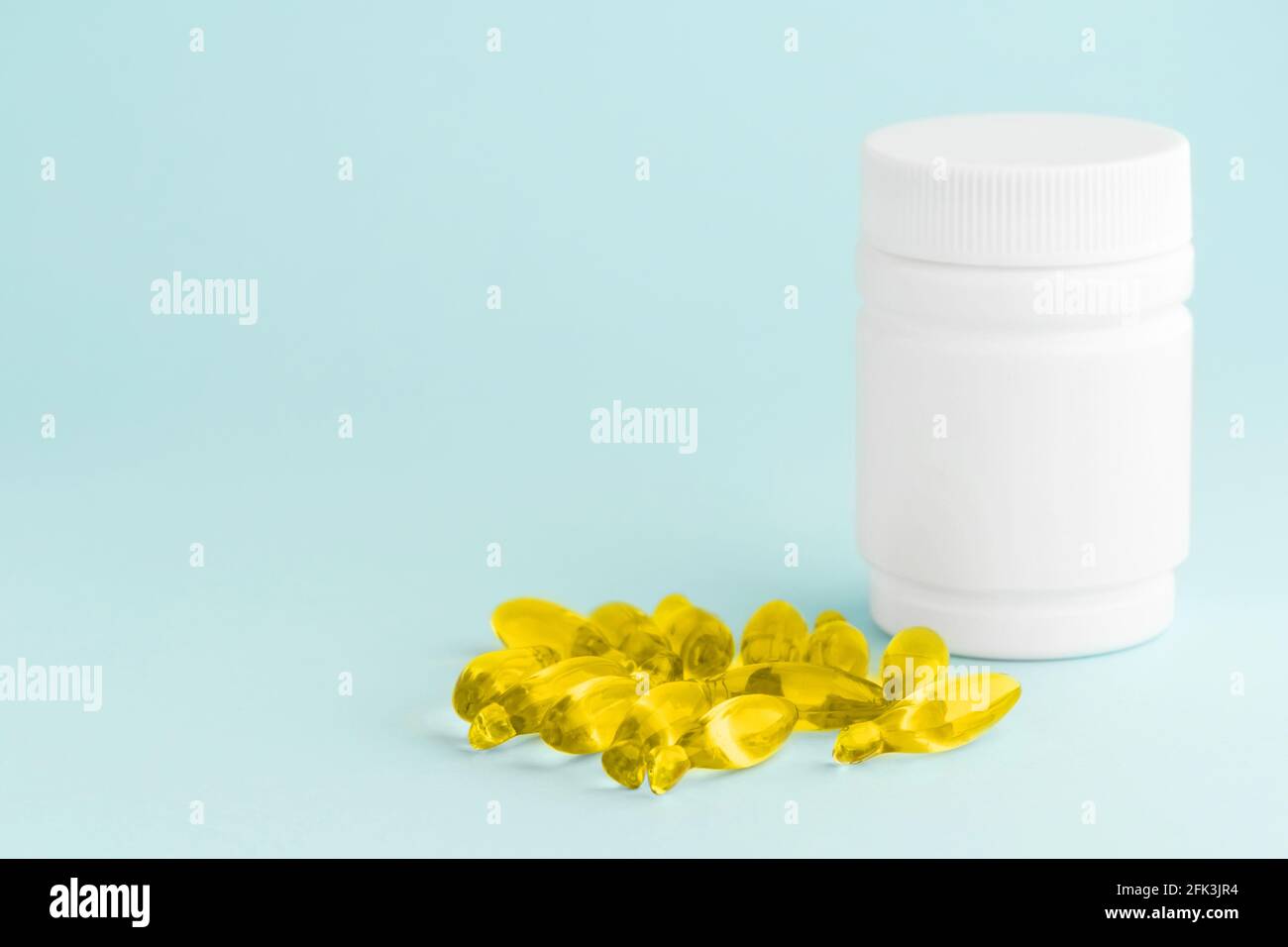 Capsules de supplément jaune d'huile de poisson omega-3 isolé et flacon en plastique blanc sur la surface bleue. Concept de soins de santé Banque D'Images