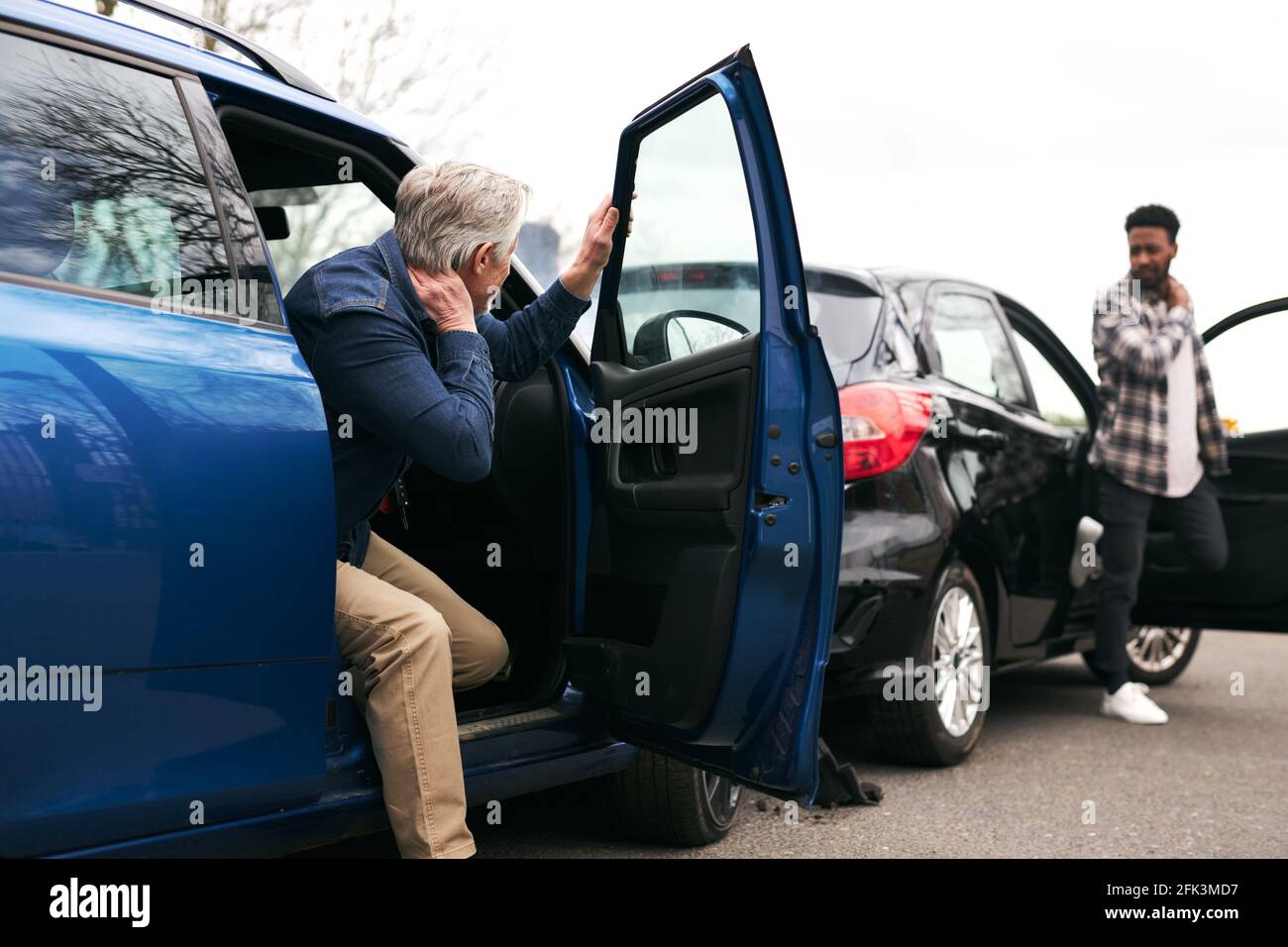 Les conducteurs de sexe masculin senior et plus jeune sortent des voitures et inspecter les dommages après un accident de la route Banque D'Images