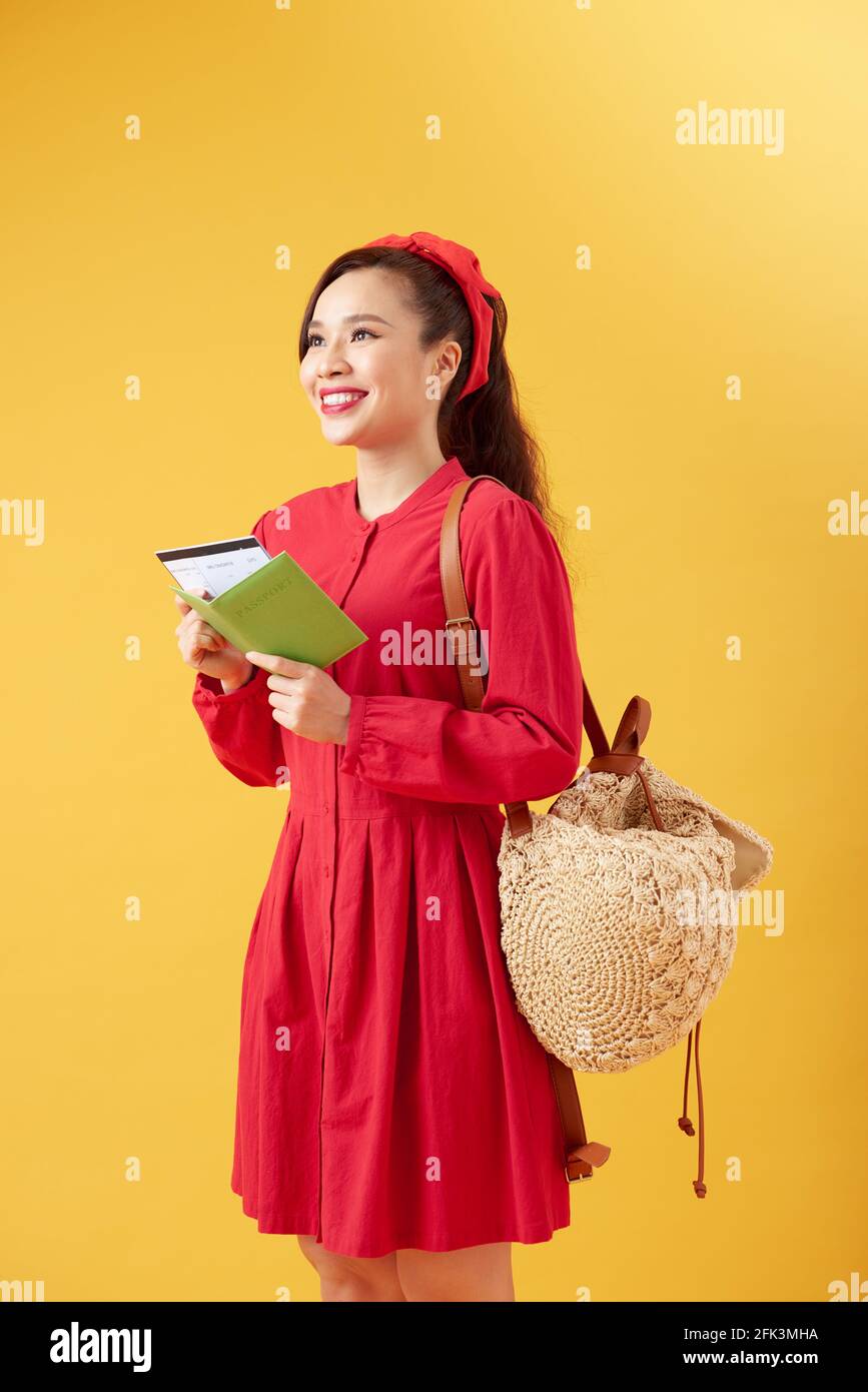 Mode de vie et de voyage concept : Full length portrait of pretty young woman holding étudiant passeport avec des billets. Isolé sur un jaune vif backg Banque D'Images