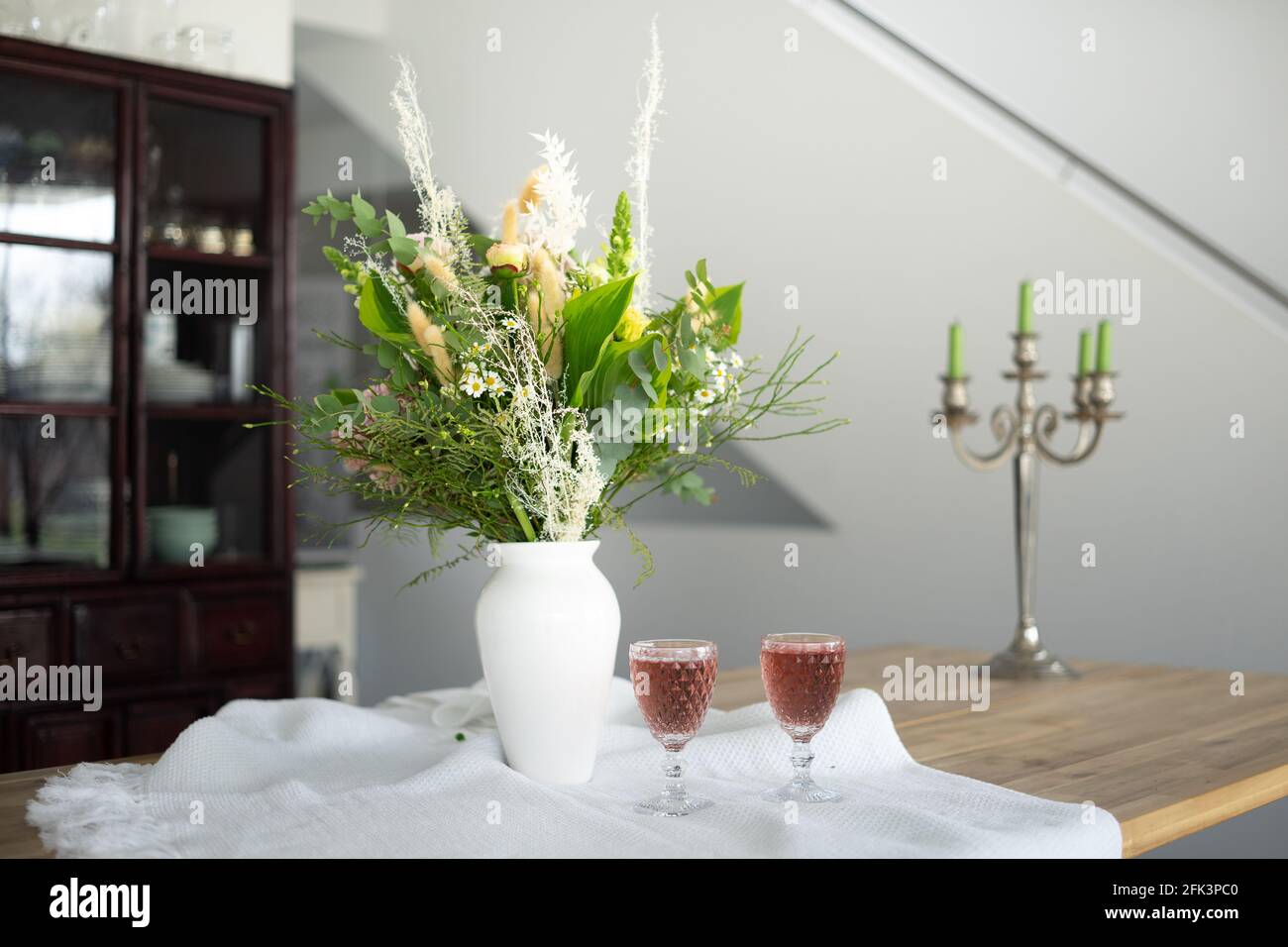 Élégant bouquet de fleurs sur une table accompagné de deux cocktails des gobelets dans une maison moderne et spacieuse Banque D'Images