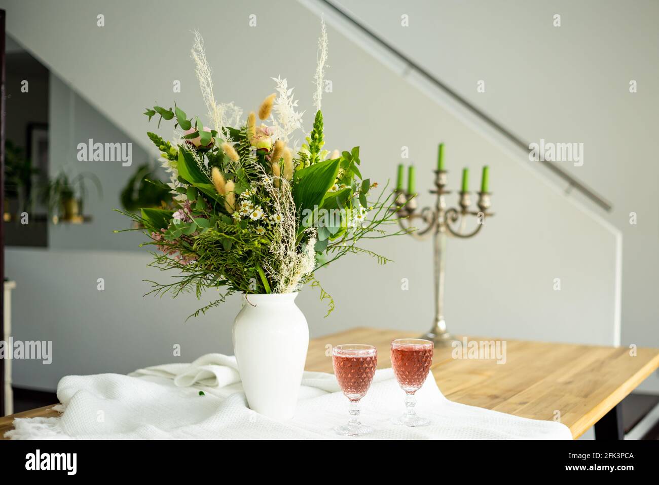 Élégant bouquet de fleurs sur une table accompagné de deux cocktails des gobelets dans une maison moderne et spacieuse Banque D'Images