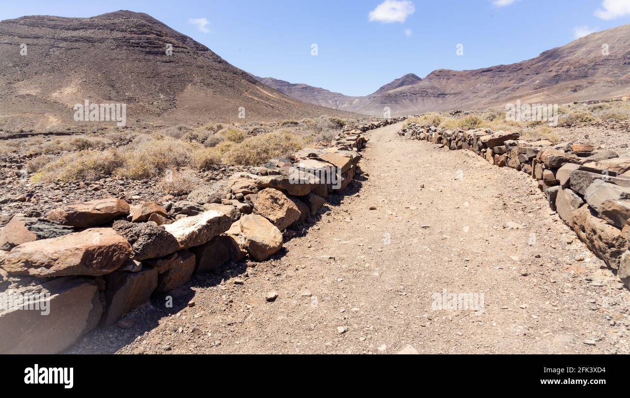 Route de poussière menant dans une vallée dans un paysage désertique Banque D'Images