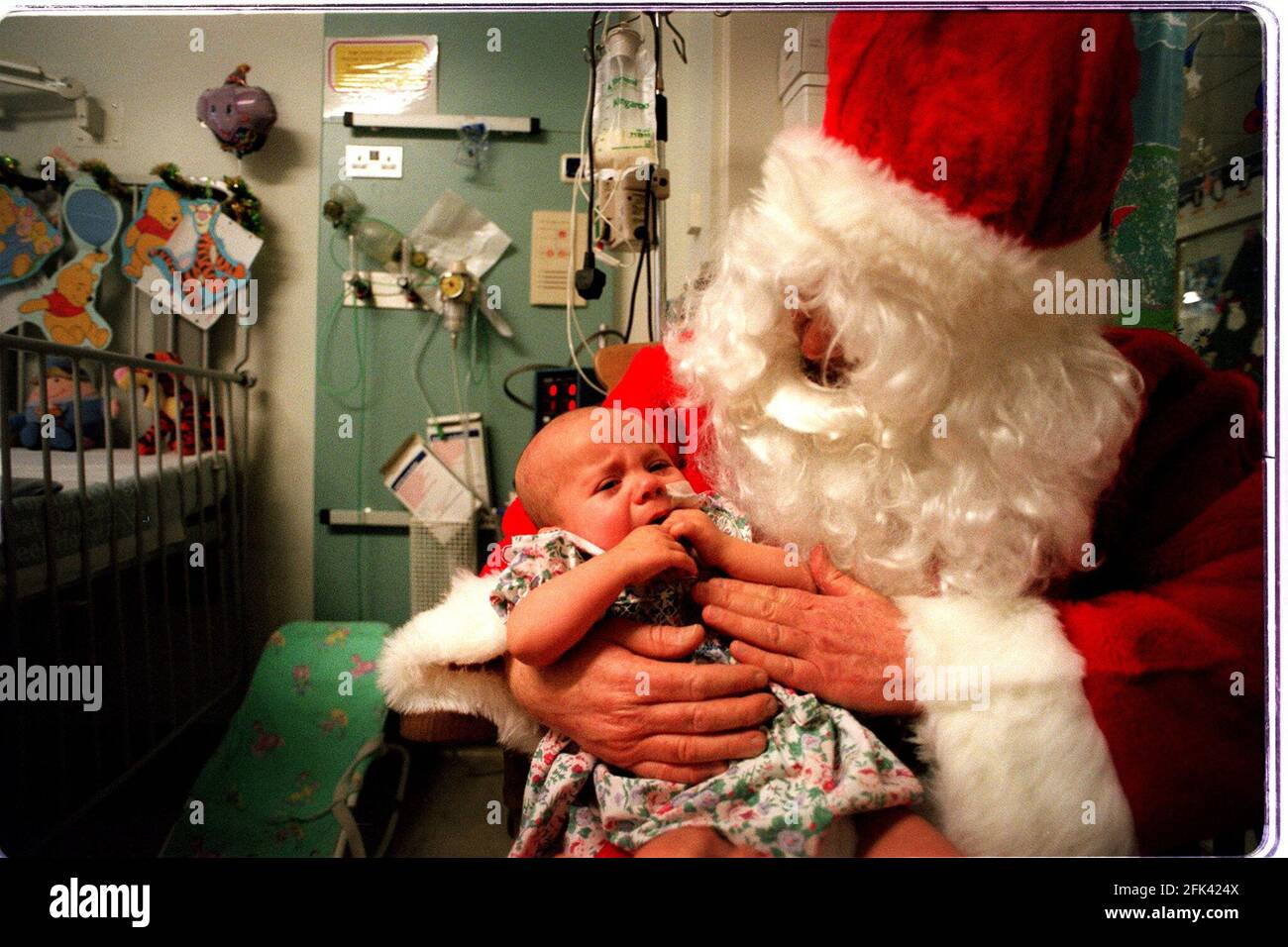 Visite de Noël de père à l'hôpital Great Ormond Street. Photos prises sur Parrot Ward (neurochirurgical). L'hôpital avait deux visites du Père Christmases; celle-ci est Peter Jardine, une infirmière principale du Théâtre cardiaque. Sophie Norman, âgée de 7 mois aujourd'hui, de Dunstable, qui a une tumeur cérébrale et un hydrocéphalie Banque D'Images