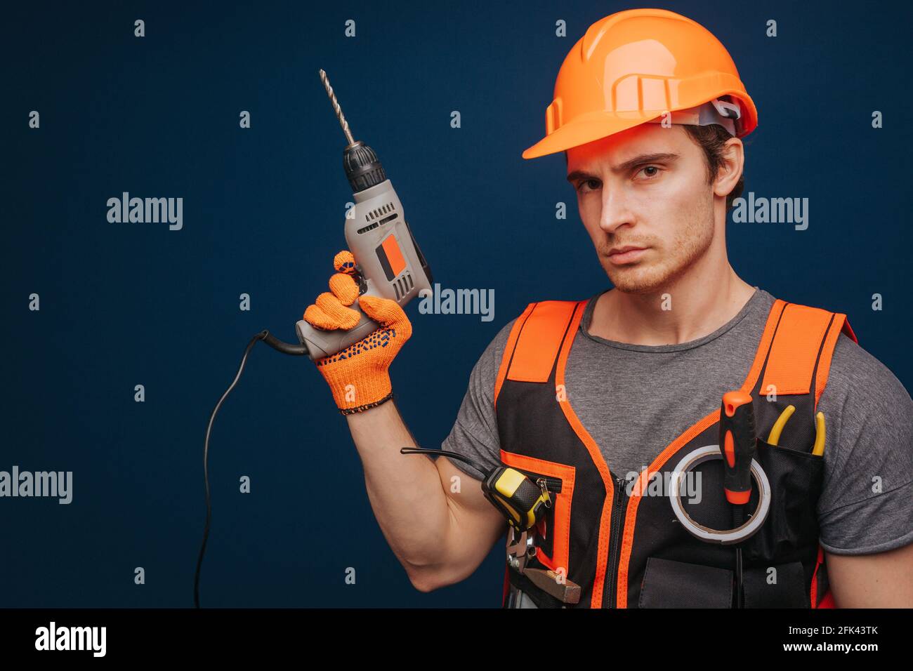 Builder a sérieusement l'équipement dans le bras, isolé sur fond bleu Banque D'Images