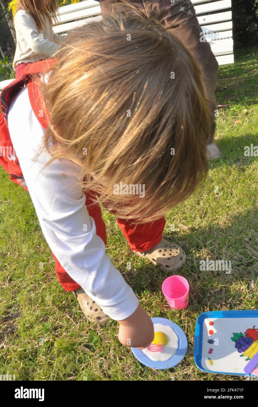 enfant vu d'en haut, jouant avec des petites assiettes et des verres en  plastique, avec un jardinier rouge et des chaussons en caoutchouc Photo  Stock - Alamy