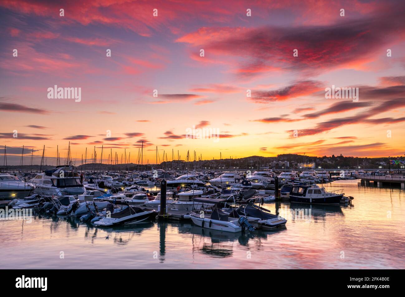 Torquay, South Devon, Angleterre. Après une journée de soleil et de douches sur la côte sud, tandis que le soleil met un ciel coloré illumine les eaux calmes de Th Banque D'Images