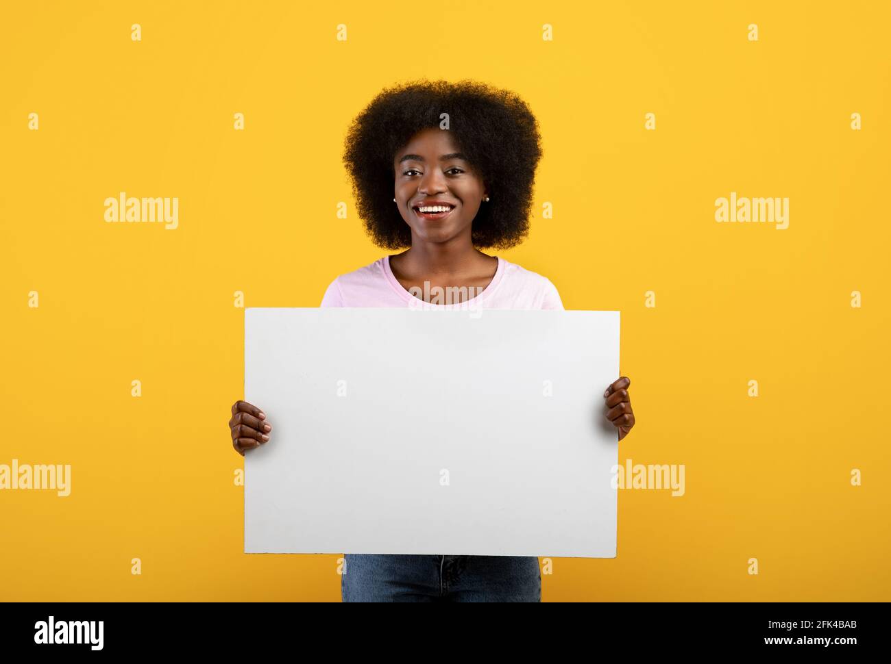 Concept de publicité. Femme noire excitée tenant un tableau vide isolé sur fond jaune de studio Banque D'Images