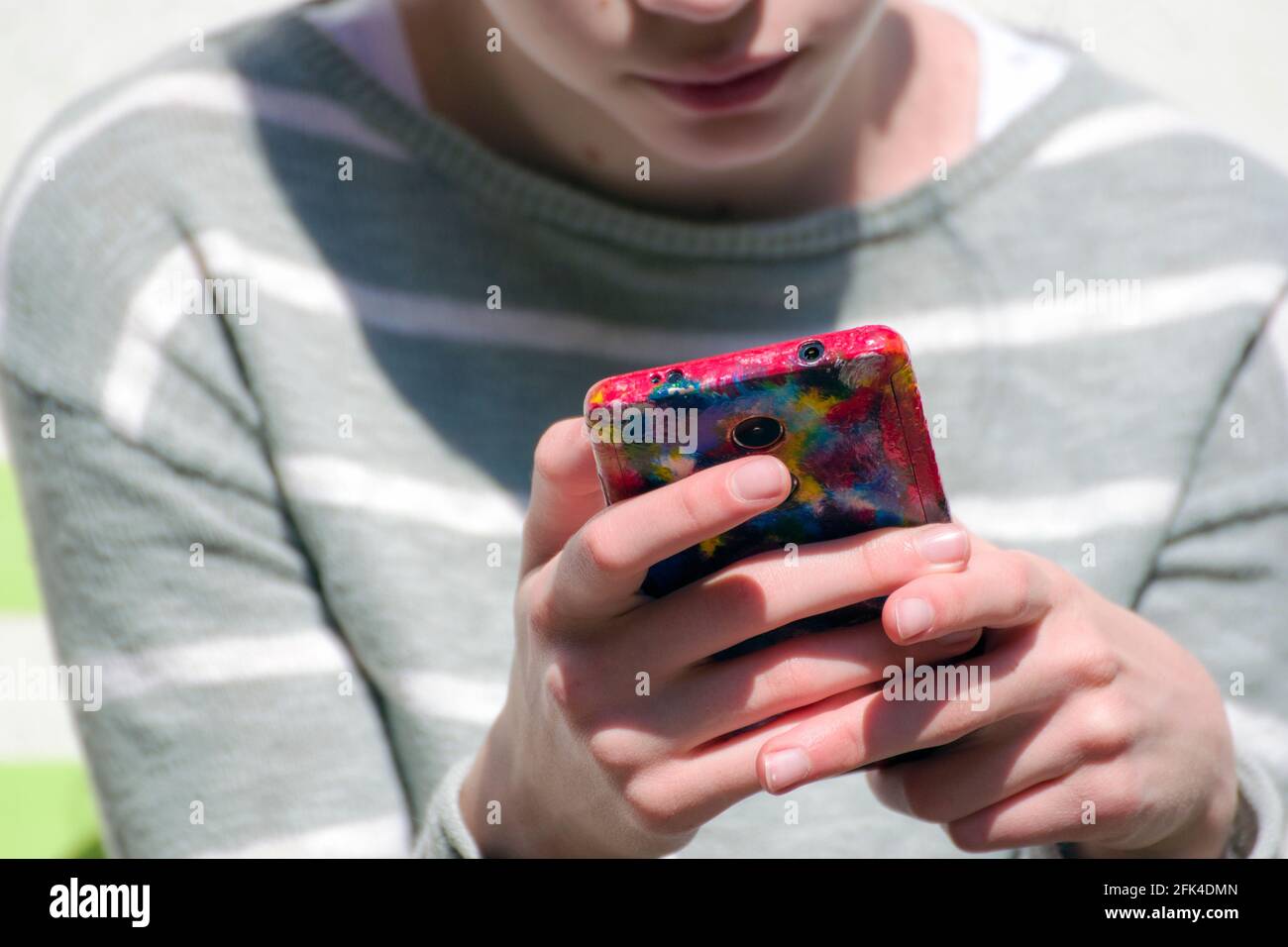 Un smartphone tenu entre les mains d'une fille ; une housse de téléphone unique peinte à la main de façon créative. Banque D'Images