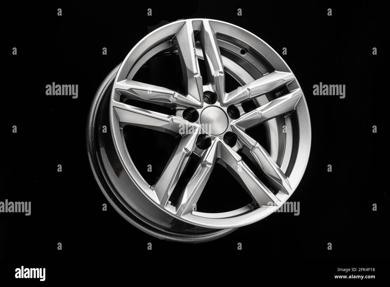 nouvelle roue en alliage argent avec poutres bifurquées sur fond noir. Banque D'Images