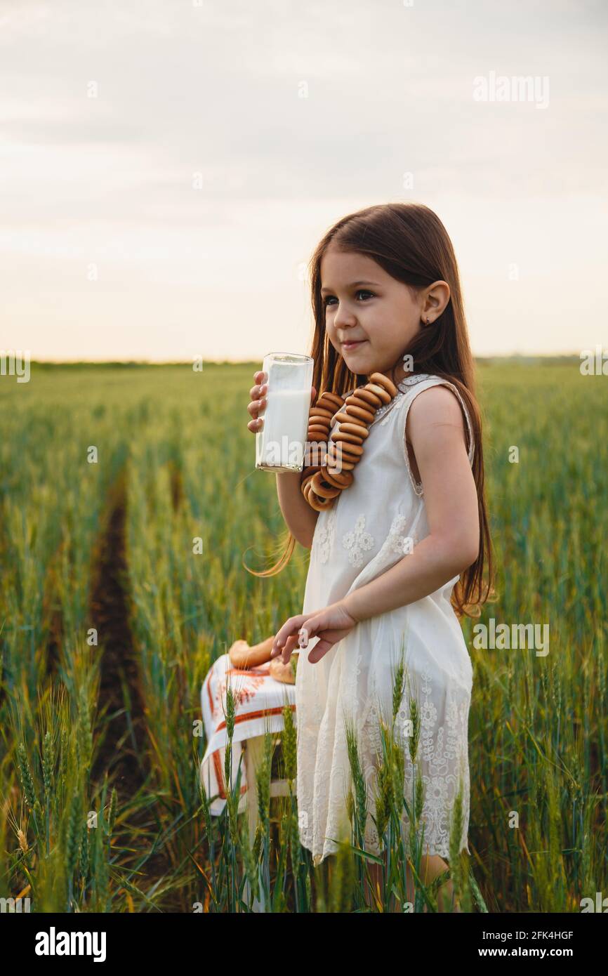 Belle petite fille en robe blanche boire du lait en vert champ Photo Stock  - Alamy