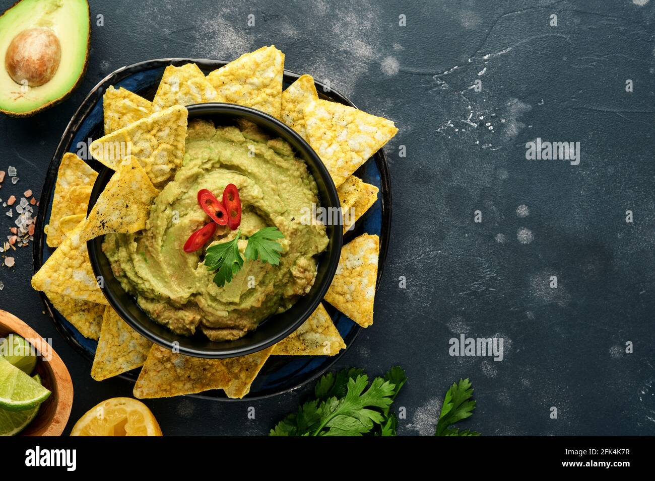 Guacamole. Sauce mexicaine traditionnelle latinaméricaine dans un bol noir avec avocat et ingrédients et nachos de maïs. Propagation de l'avocat. Vue de dessus. Copyspa Banque D'Images