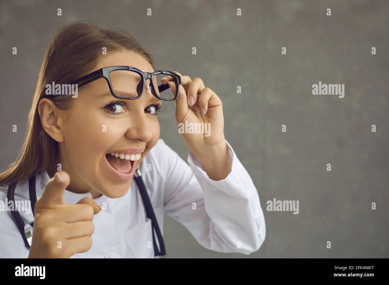 Drôle de femme médecin souriant avec la bouche ouverte pointant vers  l'appareil photo avec le doigt Photo Stock - Alamy
