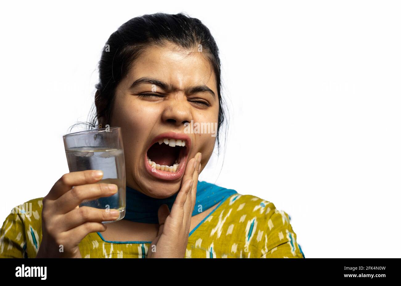 Une femme asiatique indienne avec un verre d'eau froide toucher sa joue montrant une sensibilité aux dents sur fond blanc Banque D'Images