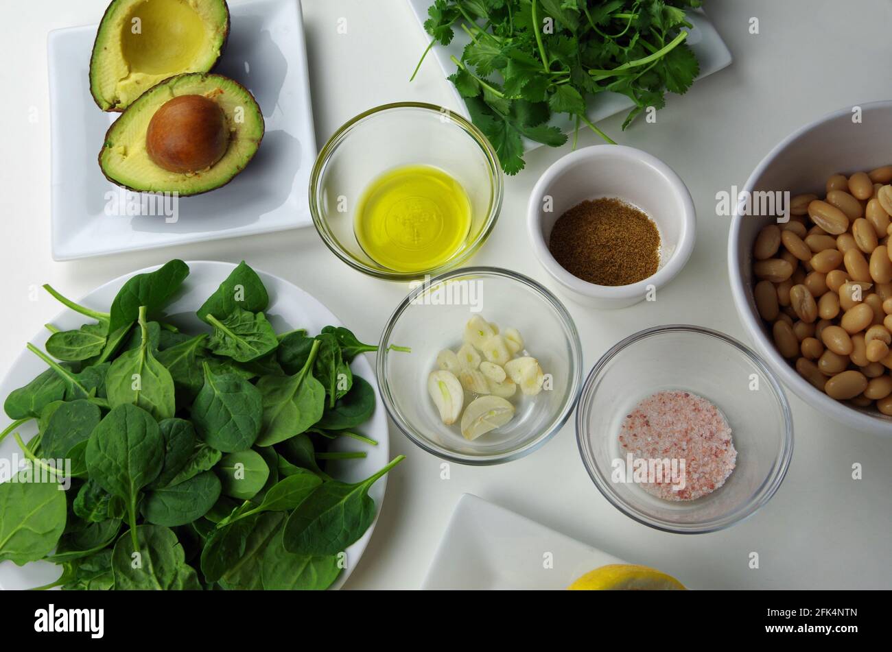 Ingrédients alimentaires sains utilisés pour préparer une délicieuse trempette, y compris l'avocat, l'huile d'olive, l'ail, le cumin, sel rose, haricots, épinards, coriandre et citron Banque D'Images