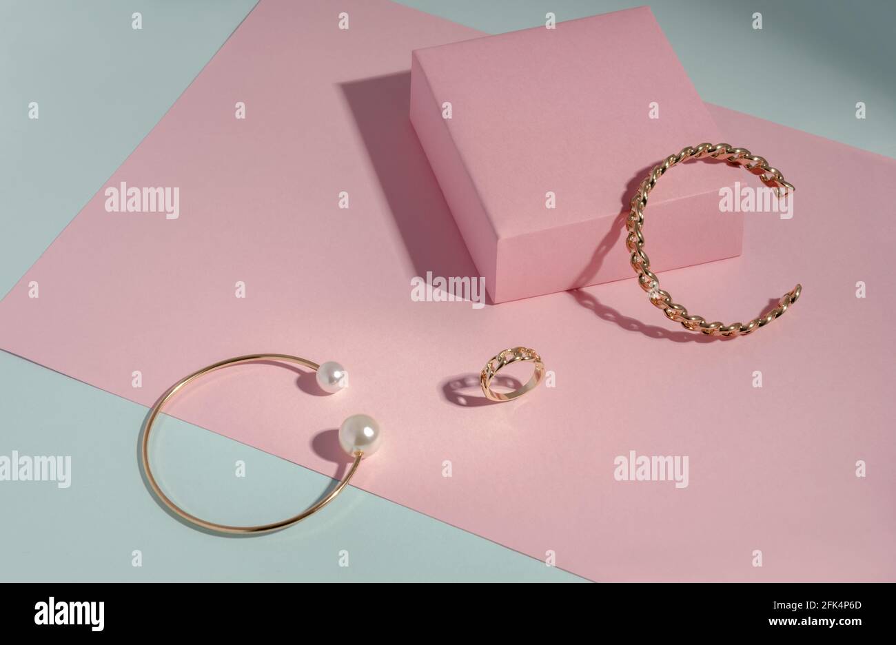 Ensemble bracelets et bagues dorés sur papier rose et bleu arrière-plan avec espace de copie Banque D'Images