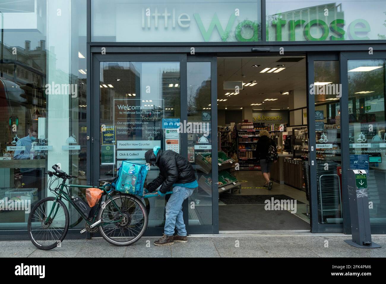 Londres, Royaume-Uni. 28 avril 2021. Un pilote Deliveroo collecte une commande en dehors d'une succursale de Waitrose dans Bankside. Waitrose et Deliveroo ont annoncé un partenariat de deux ans pour des livraisons de maisons rapides qui créera 400 nouveaux emplois à Waitrose pour remplir les commandes devant être collectées par Deliveroo. Le nouvel accord vient après que Waitrose et le épicier en ligne Ocado ont fini de travailler ensemble l'année dernière. Credit: Stephen Chung / Alamy Live News Banque D'Images