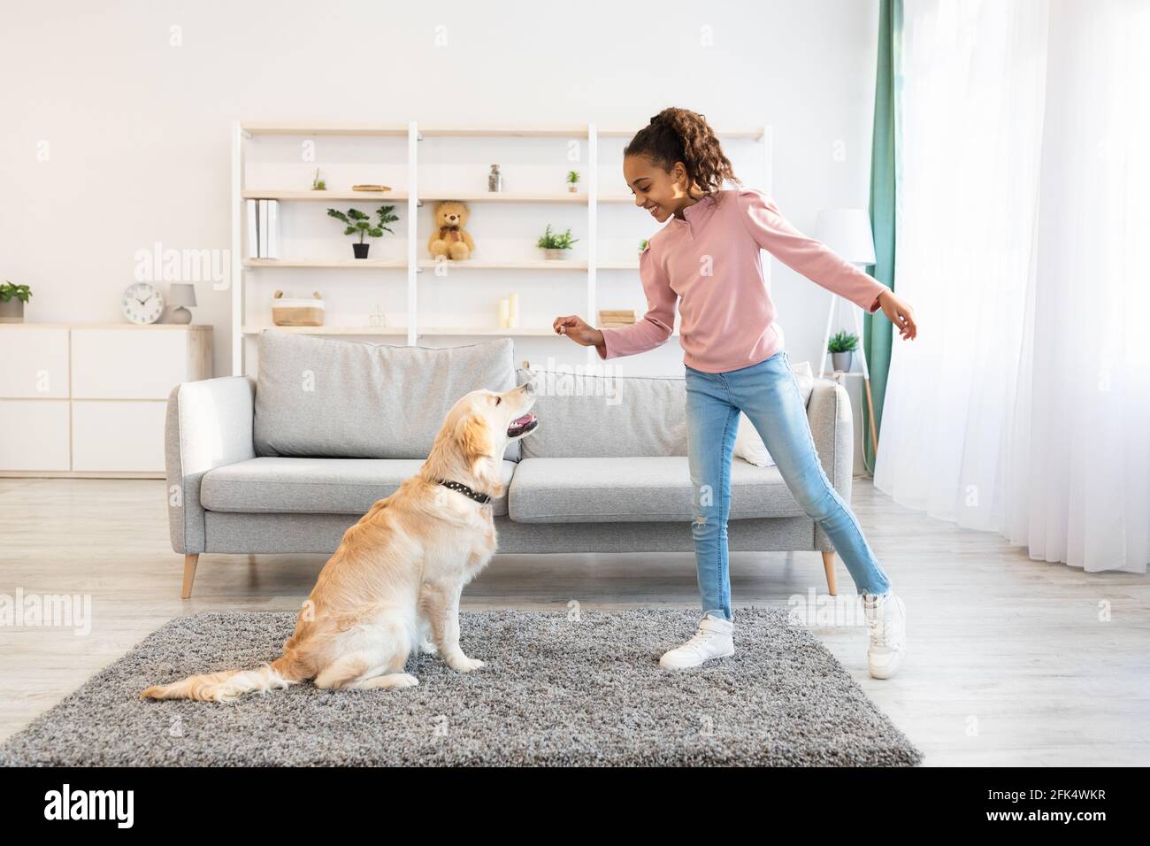 La jeune fille noire s'entraîne et donne le traitement à son chien obéissant Banque D'Images