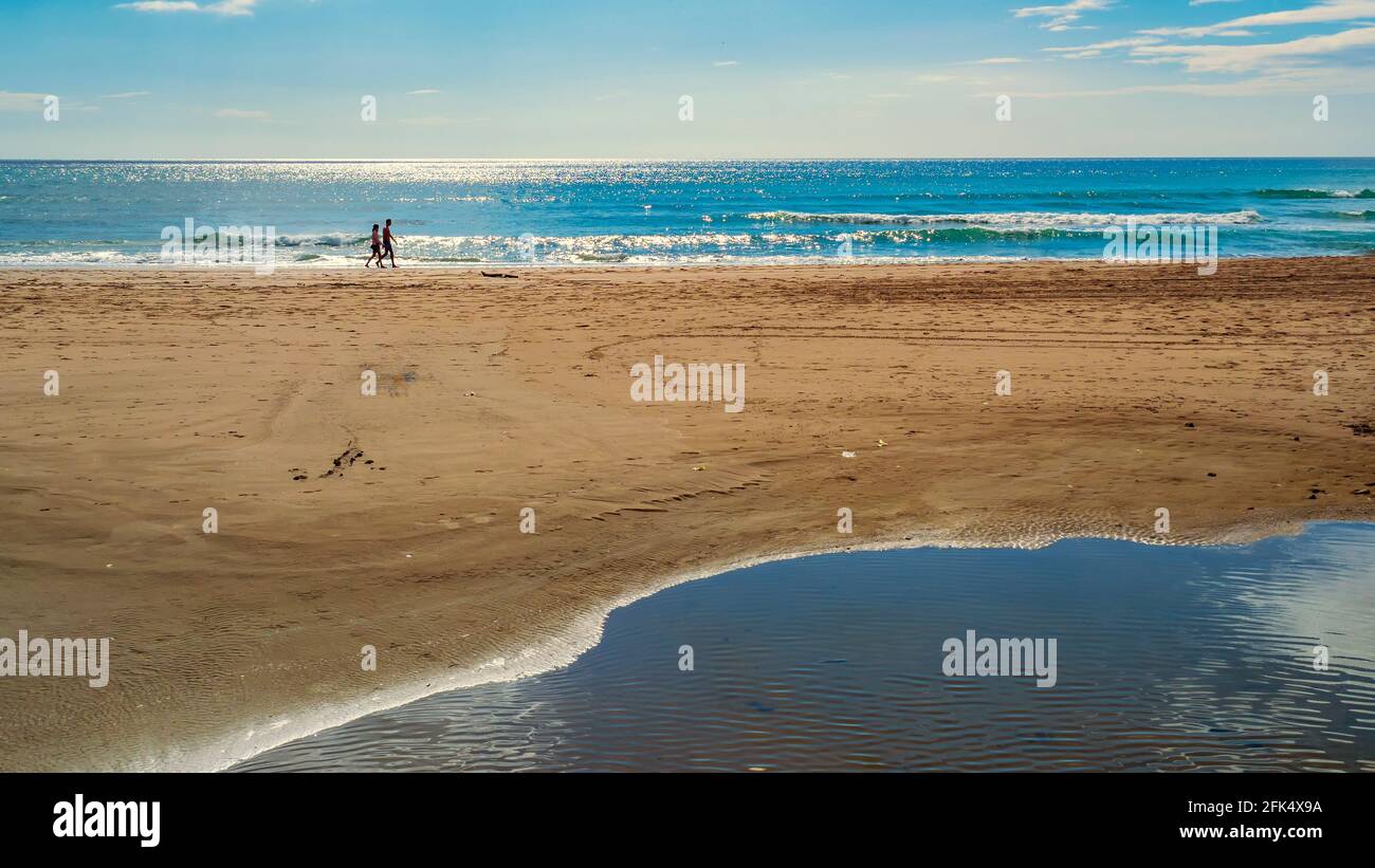 Couple marchant le long du rivage de la plage de Marbella lors d'une journée de printemps ensoleillée. Banque D'Images
