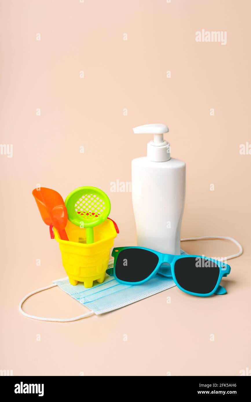 Masque chirurgical de protection avec lunettes de soleil, seau de plage et bouteille en plastique de SunScreen.Summer concept avec Covid-19 Banque D'Images