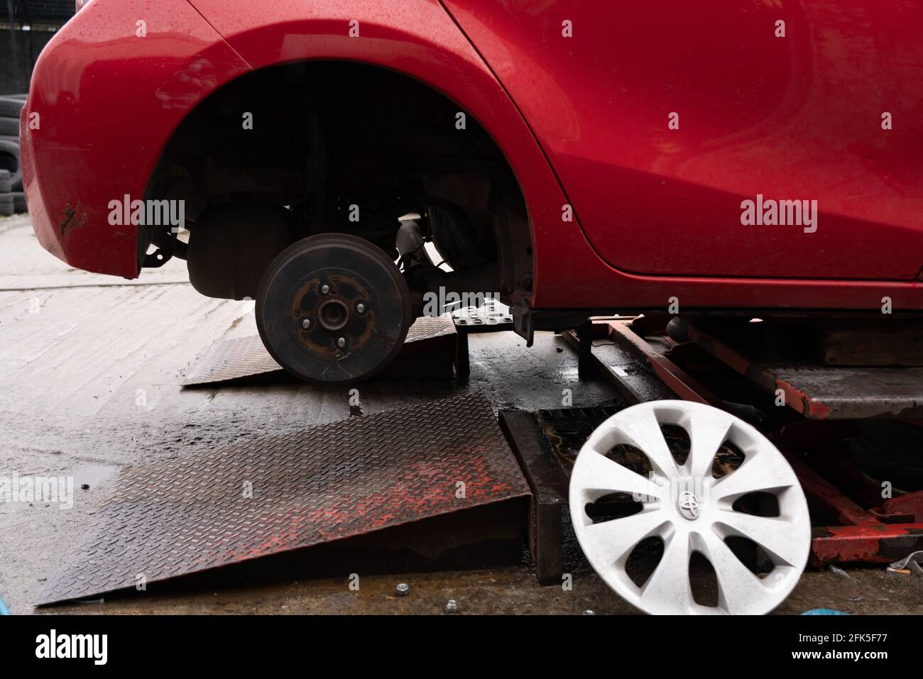 roue démontée de la voiture rouge en cours de réparation Banque D'Images