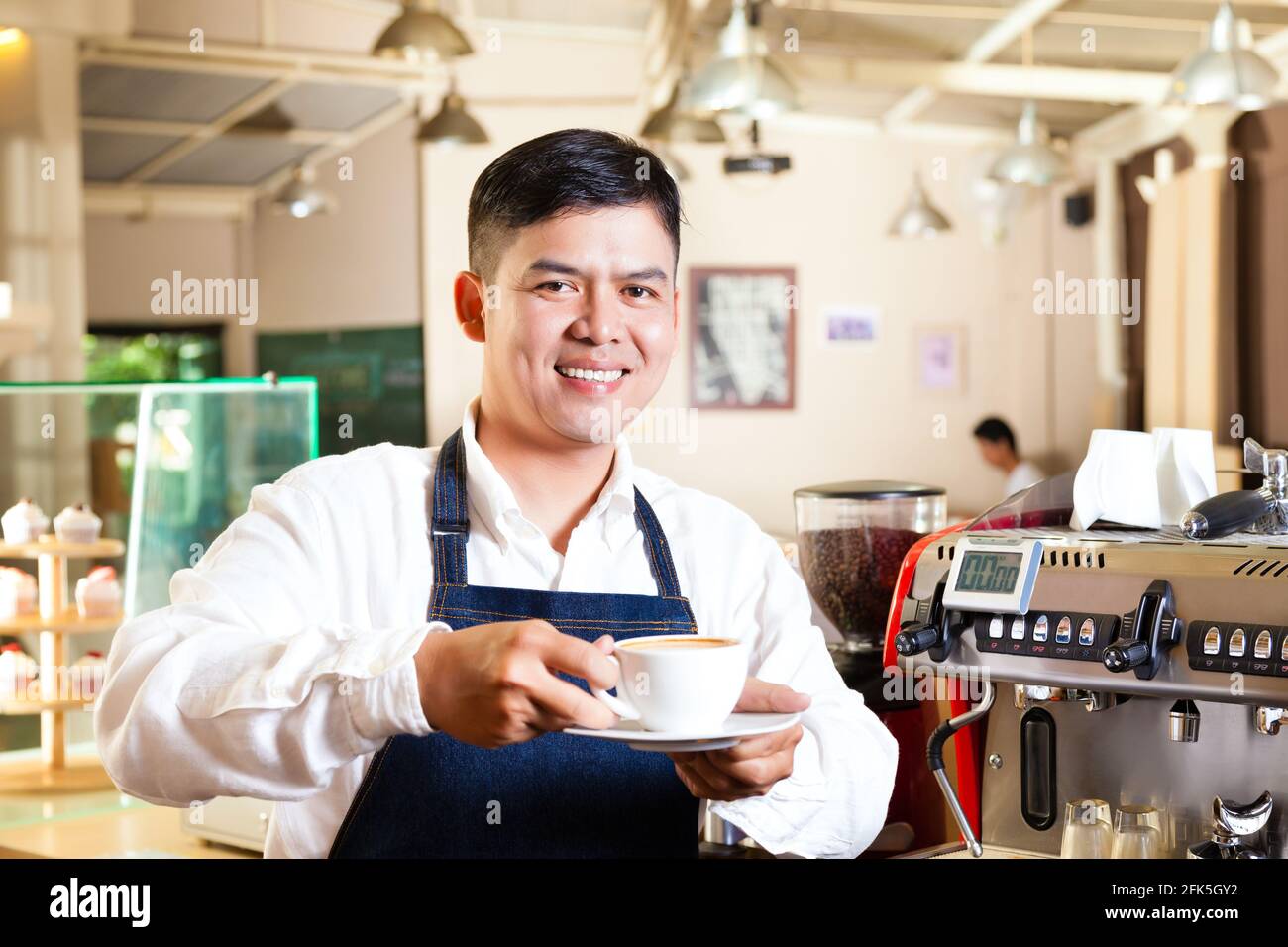 Coffeeshop - café barista asiatique présente dans son magasin Banque D'Images