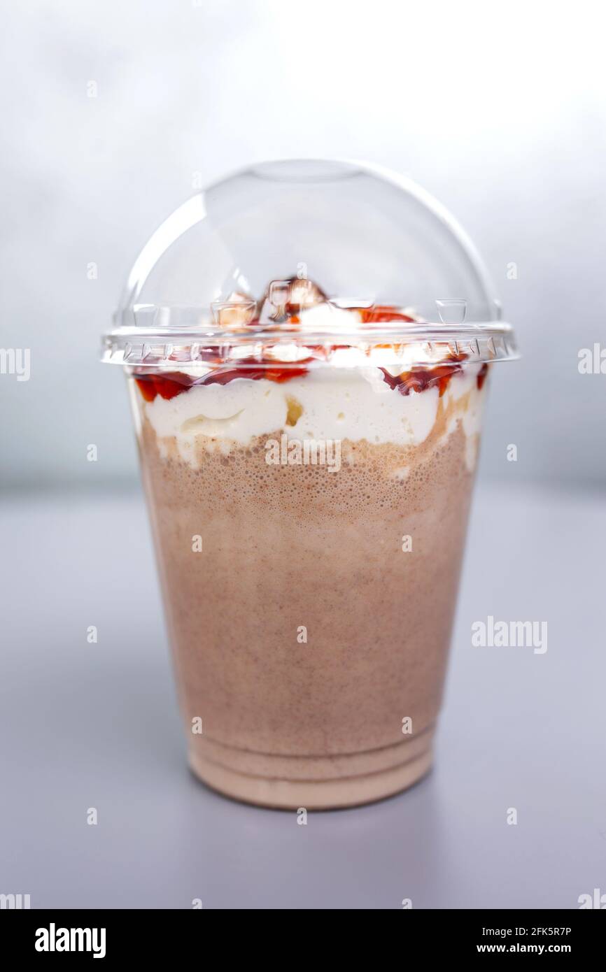 boisson au lait sucré dans un verre de plastique sur fond gris. Banque D'Images