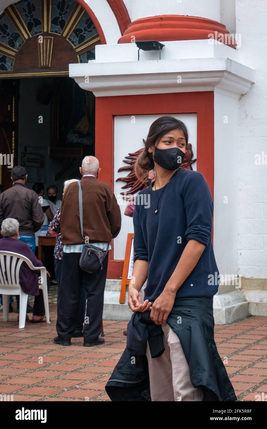 Guatape, Antioquia, Colombie - avril 4 2021 : jeune femme asiatique portant un masque noir devant une Église Banque D'Images
