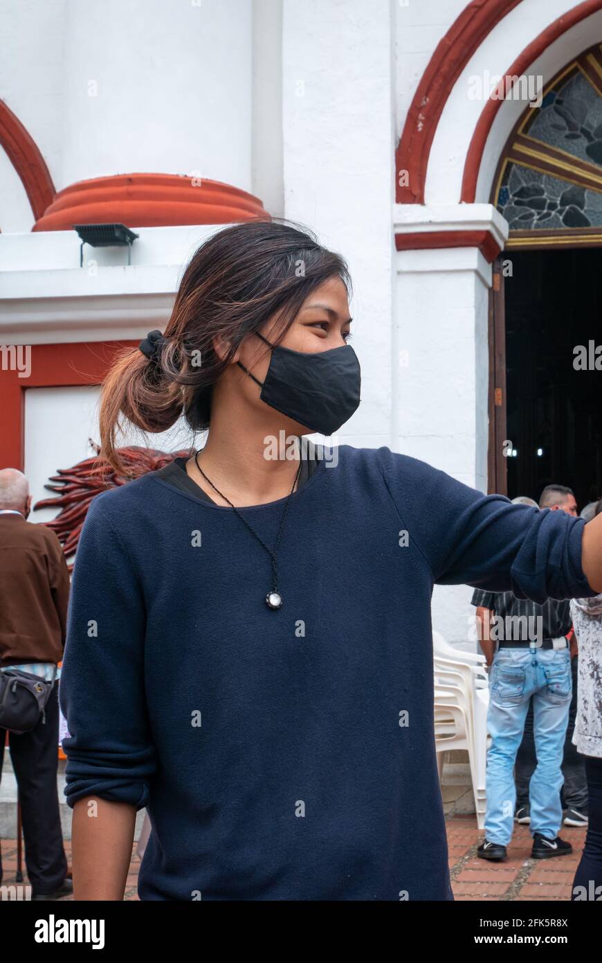 Guatape, Antioquia, Colombie - avril 4 2021 : jeune femme asiatique portant un masque noir devant une Église Banque D'Images