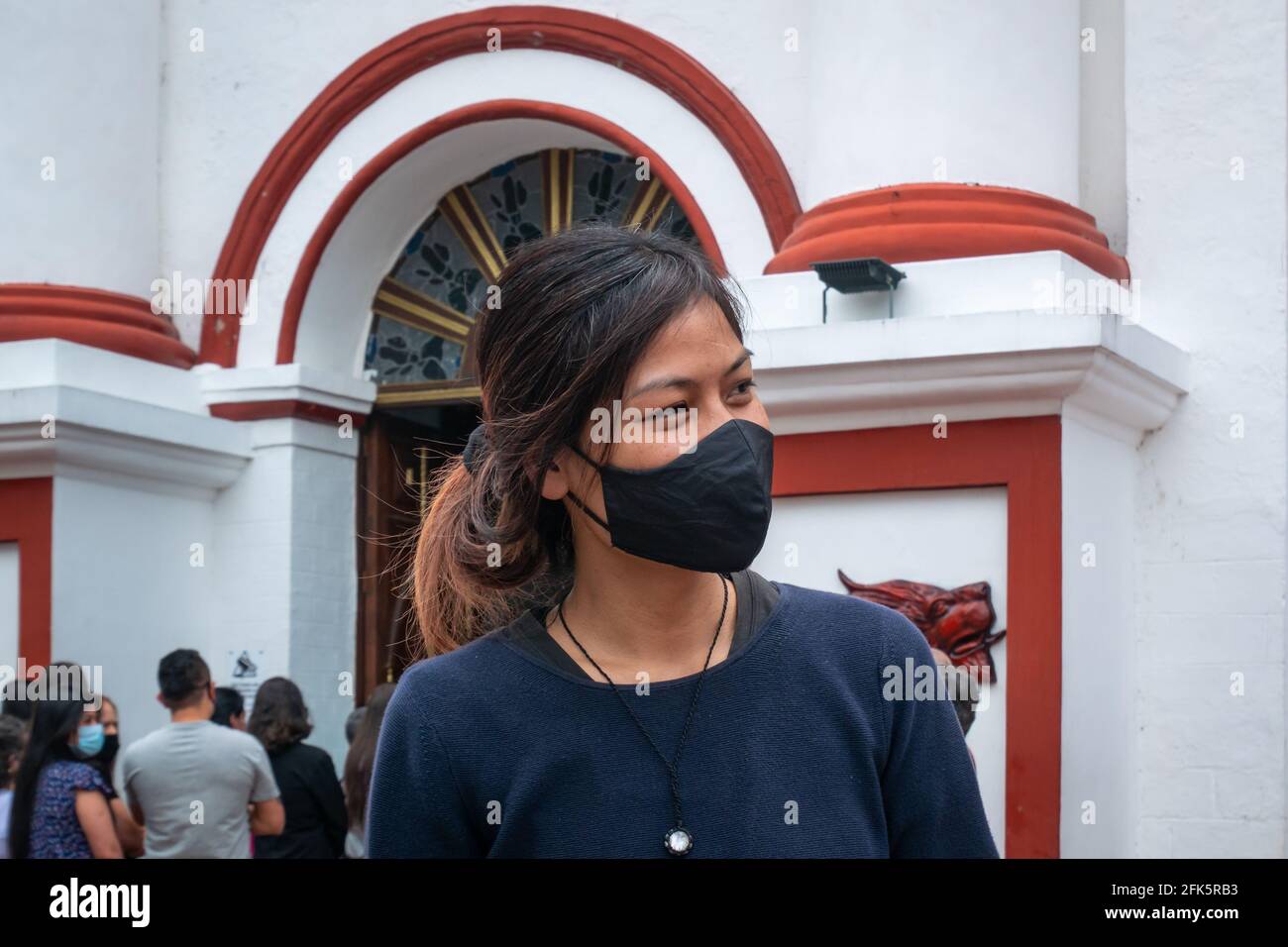 Guatape, Antioquia, Colombie - avril 4 2021 : jeune femme asiatique portant un masque noir devant une Église Banque D'Images