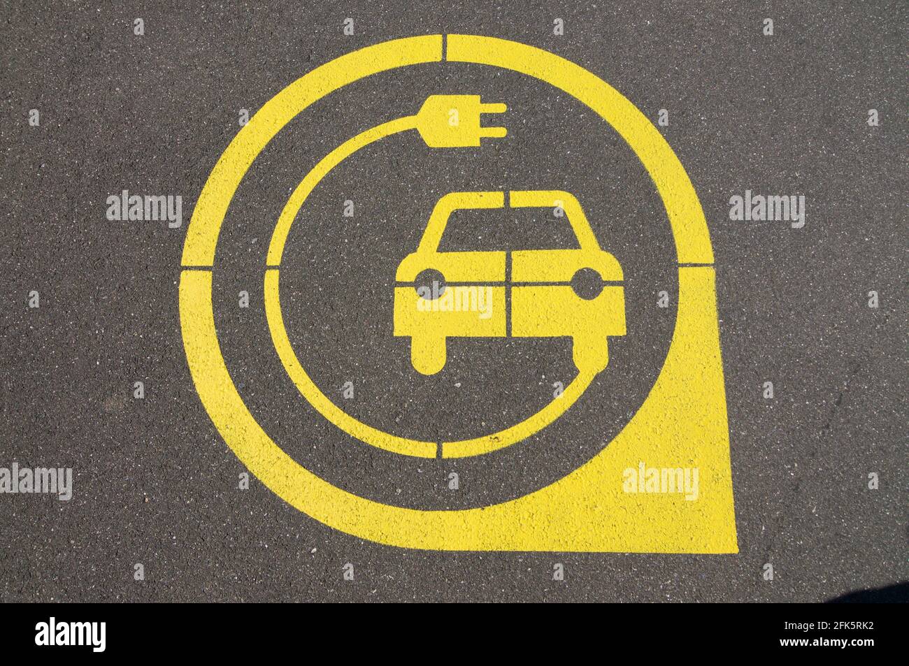 Symbole jaune de station de charge de véhicule électrique sur asphalte noir situé dans la ville de Zug, Suisse Banque D'Images