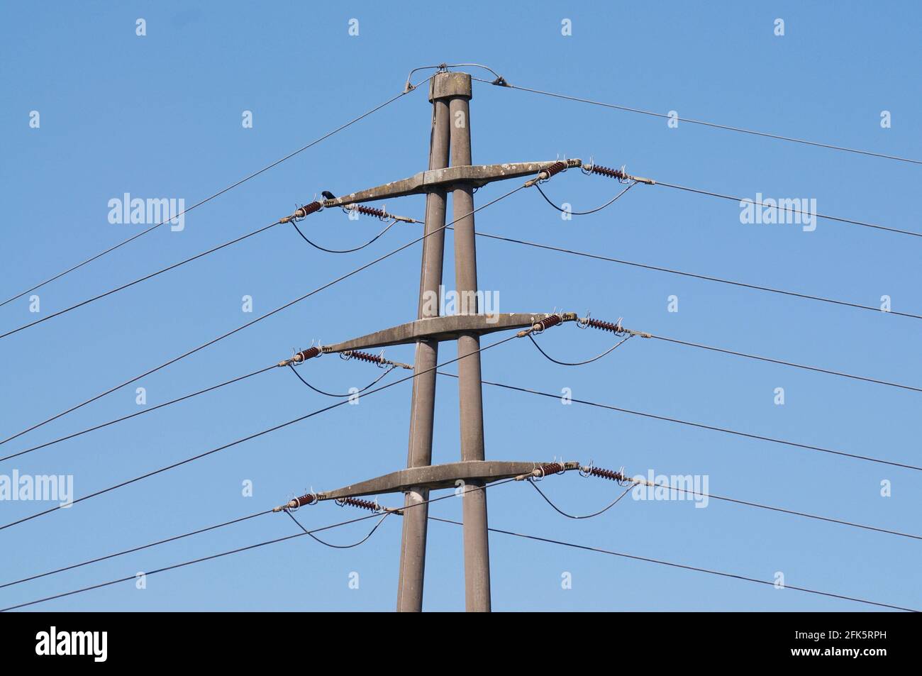 Vue sur une pierre à haute tension de transmission électrique pylône contre Ciel bleu en Suisse Banque D'Images