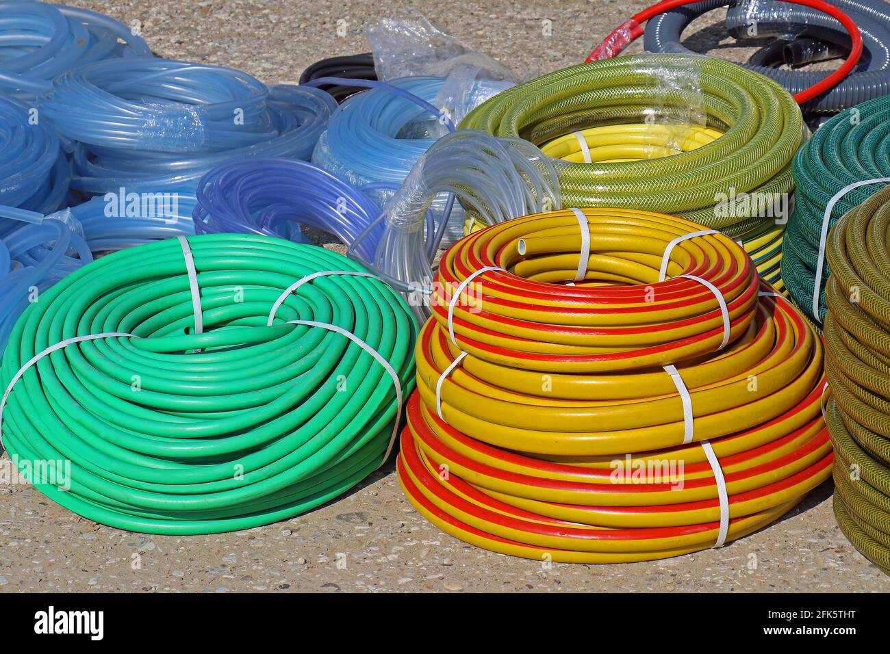 Équipement de jardin pile de tuyaux d'eau en plastique coloré sur le marché sol Banque D'Images