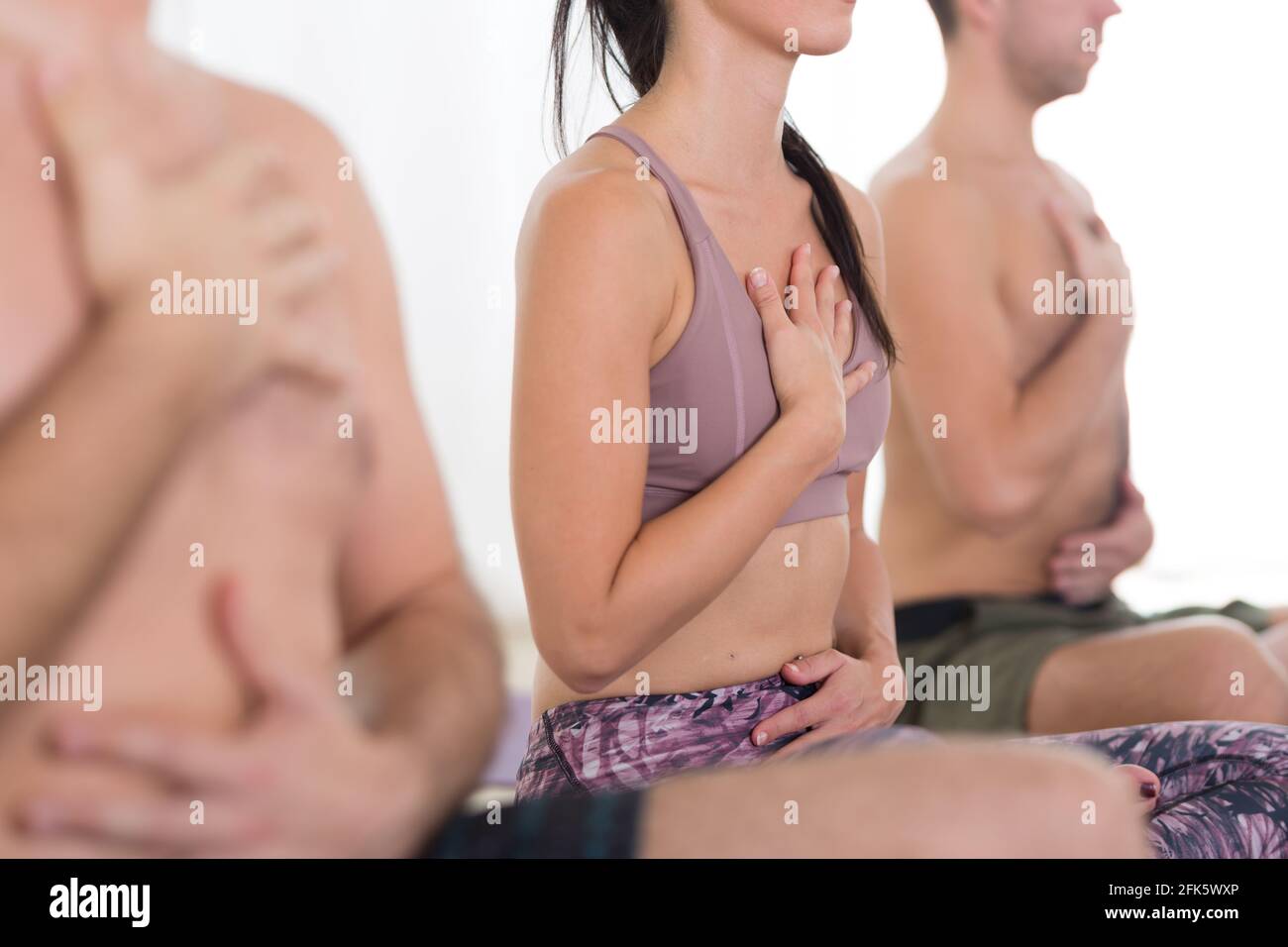 Groupe de jeunes sportifs attirants personnes pratiquant la leçon de yoga avec un instructeur dans un studio moderne de yoga lumineux. Banque D'Images