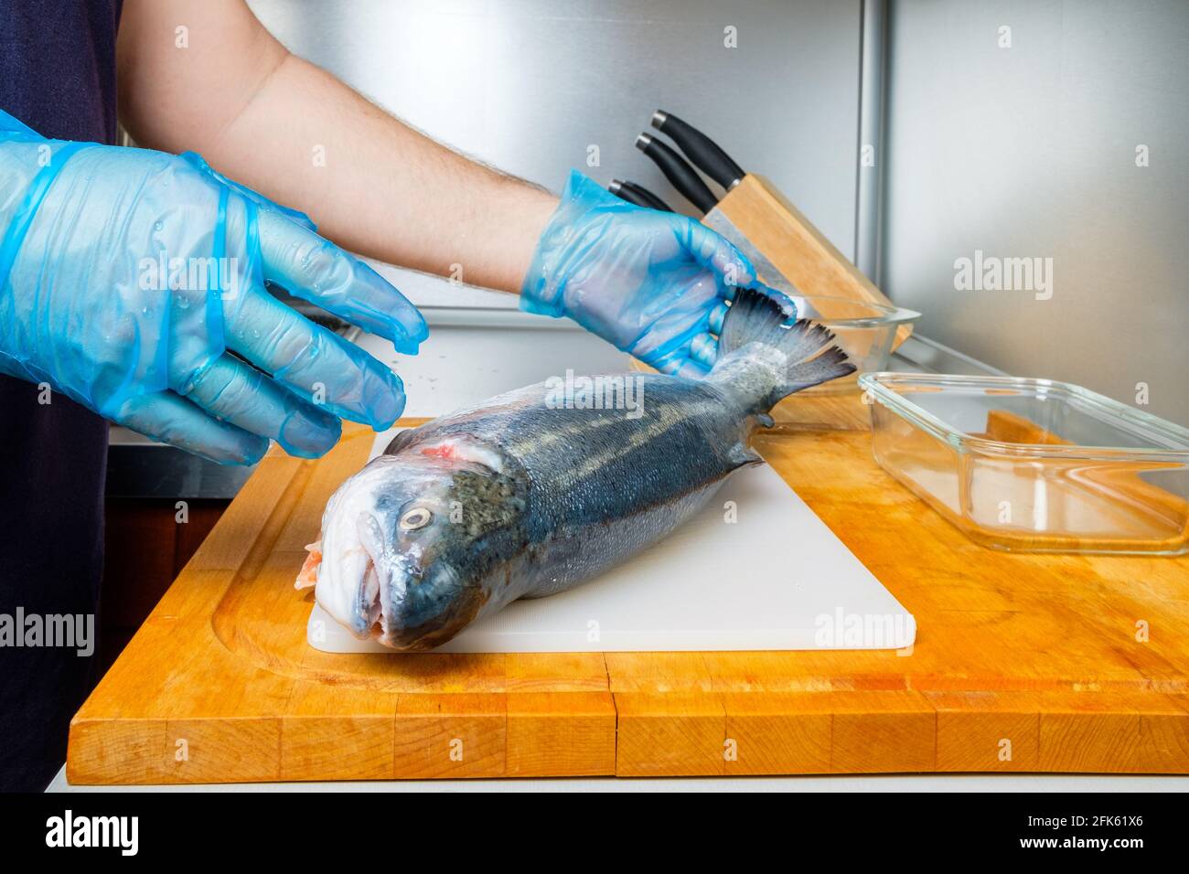 Un cuisinier en gants hygiéniques tient le tronc d'un saumon frais.  Préparation pour couper du poisson dans la cuisine sur une planche à  découper Photo Stock - Alamy