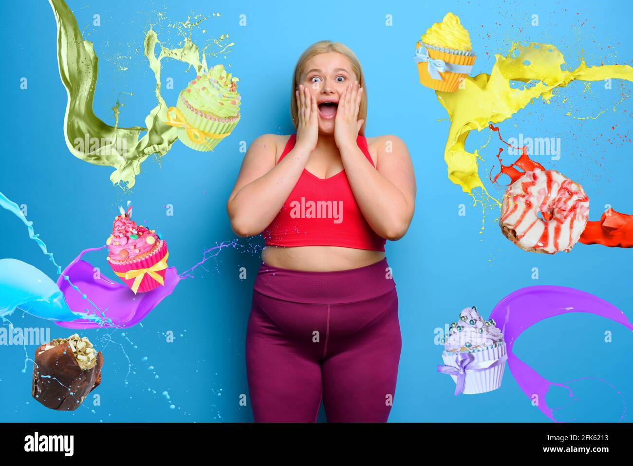 Femme grasse avec une expression choquée et surprise parce qu'elle est entourée de bonbons. Fond cyan Banque D'Images