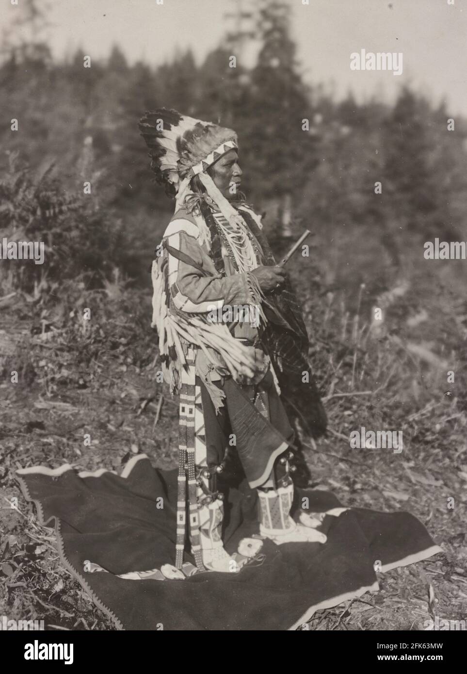White Bird - la photographie montre White Bird, un Indien américain de la région du plateau, portrait pleine longueur, debout, face à gauche, portant la plume de headaddress - Frank Woodfield, 1911 Banque D'Images