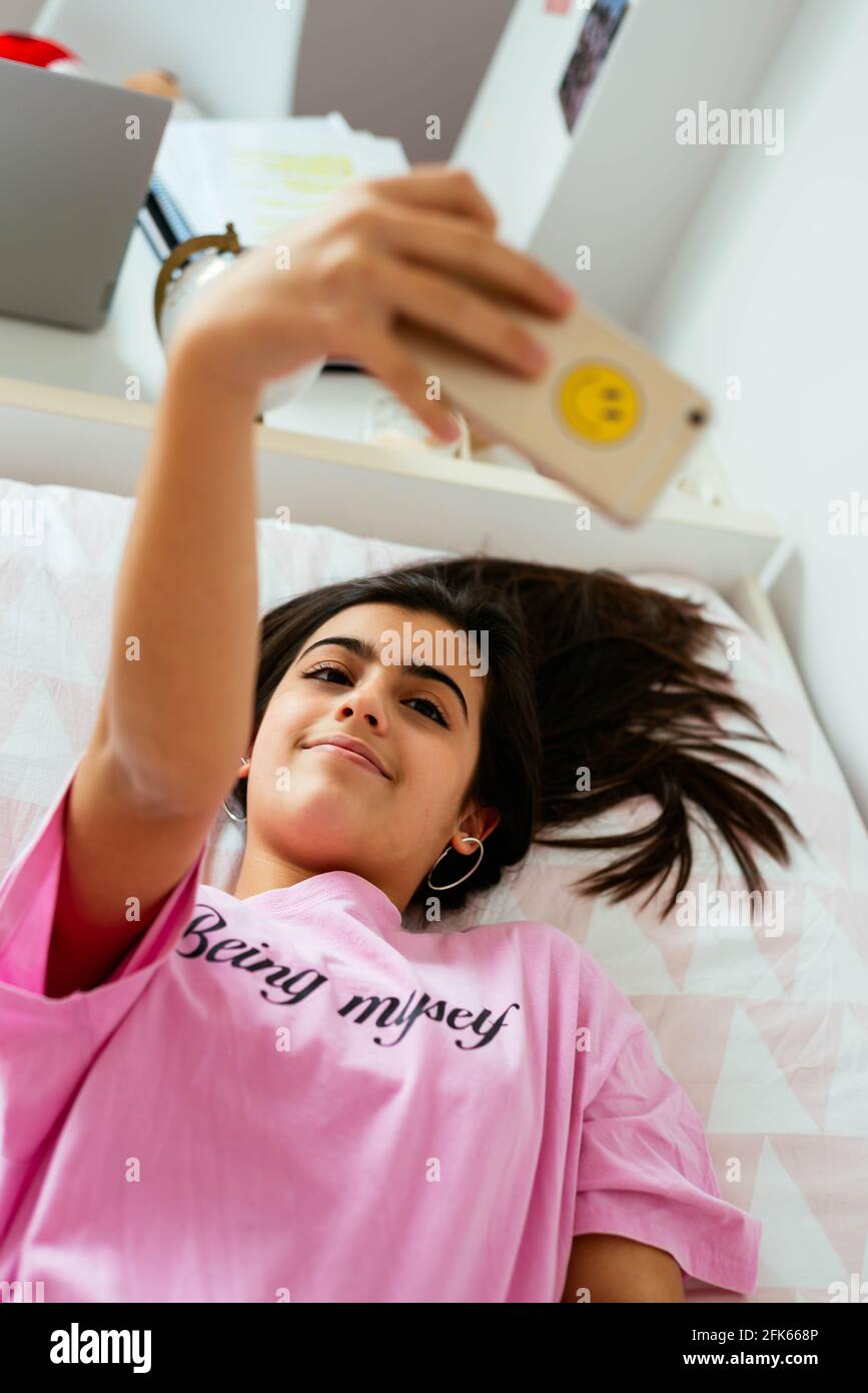 Femme adolescente utilisant un smartphone sur le lit et prenant des photos Banque D'Images