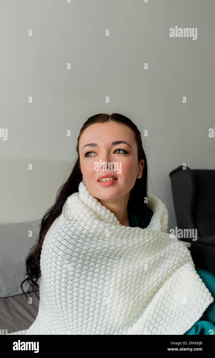 La jeune femme est enveloppée de tissu écossais blanc tout en étant assise sur le lit dans la chambre. Banque D'Images