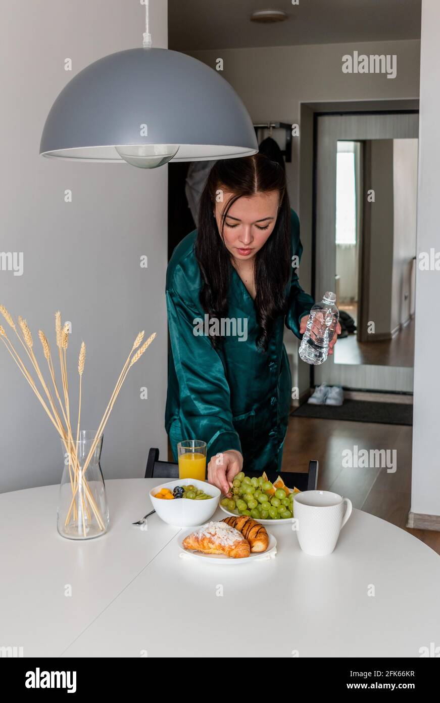 Jeune femme pyjama en soie a le petit déjeuner dans la cuisine à la maison. Concept bien-être. Banque D'Images