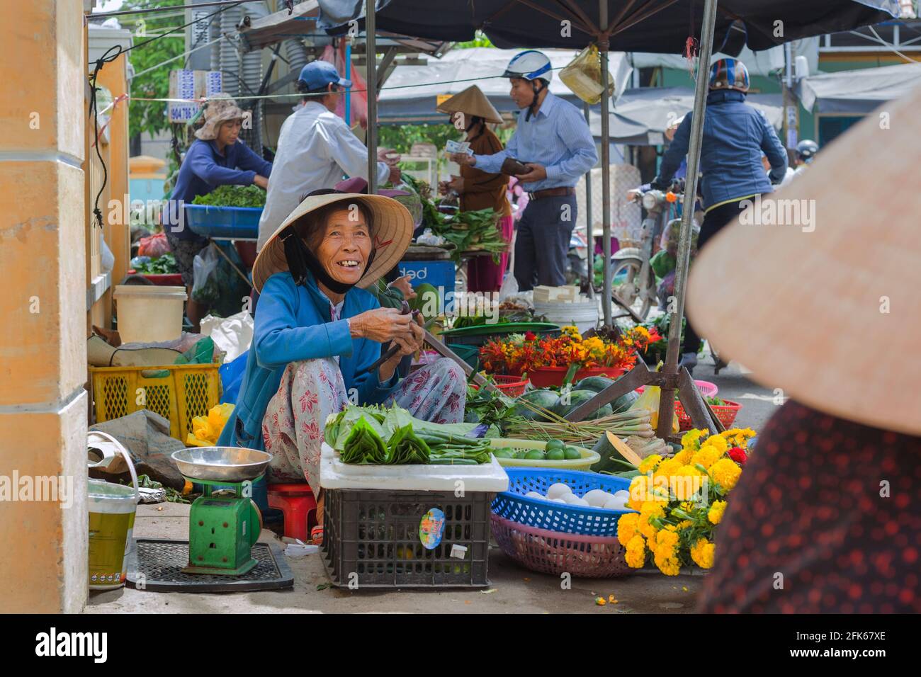 Marchand vietnamien vendant des fleurs et des légumes sur le côté de la route, Hoi an, Vietnam Banque D'Images