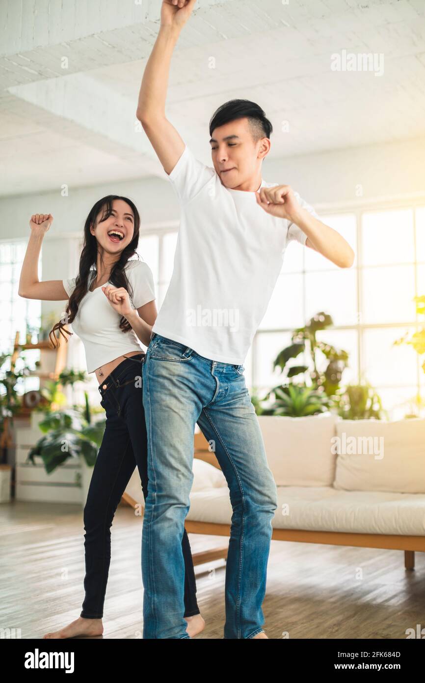 Joyeux jeune couple dansant dans le salon à la maison Banque D'Images