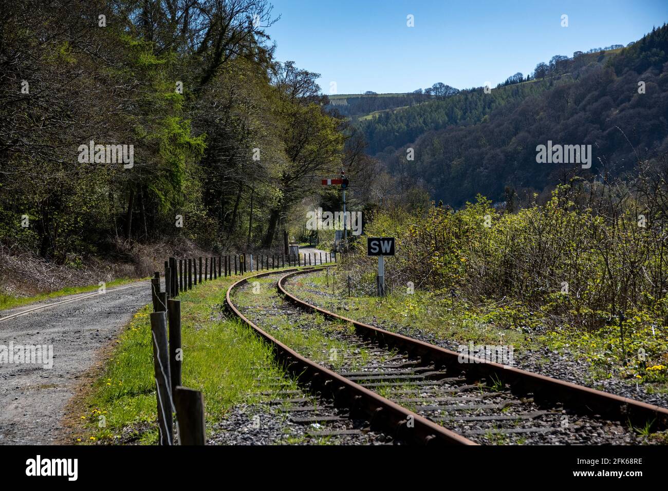 voies de chemin de fer sur un coin à côté d'une route de terre avec un signal sur le côté Banque D'Images